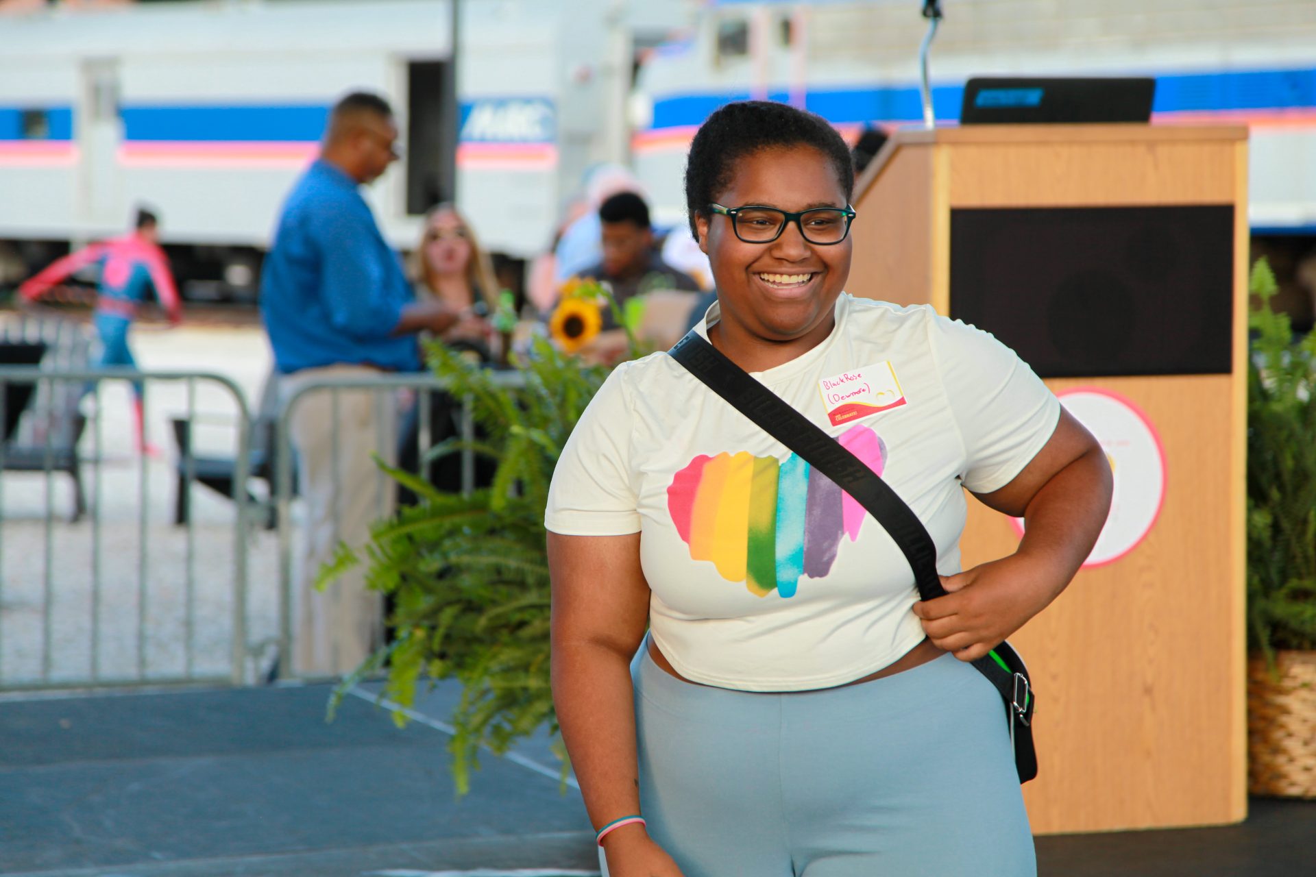 A young Black woman in a white t-shirt with a rainbow heart poses for the camera after reciting a poem
