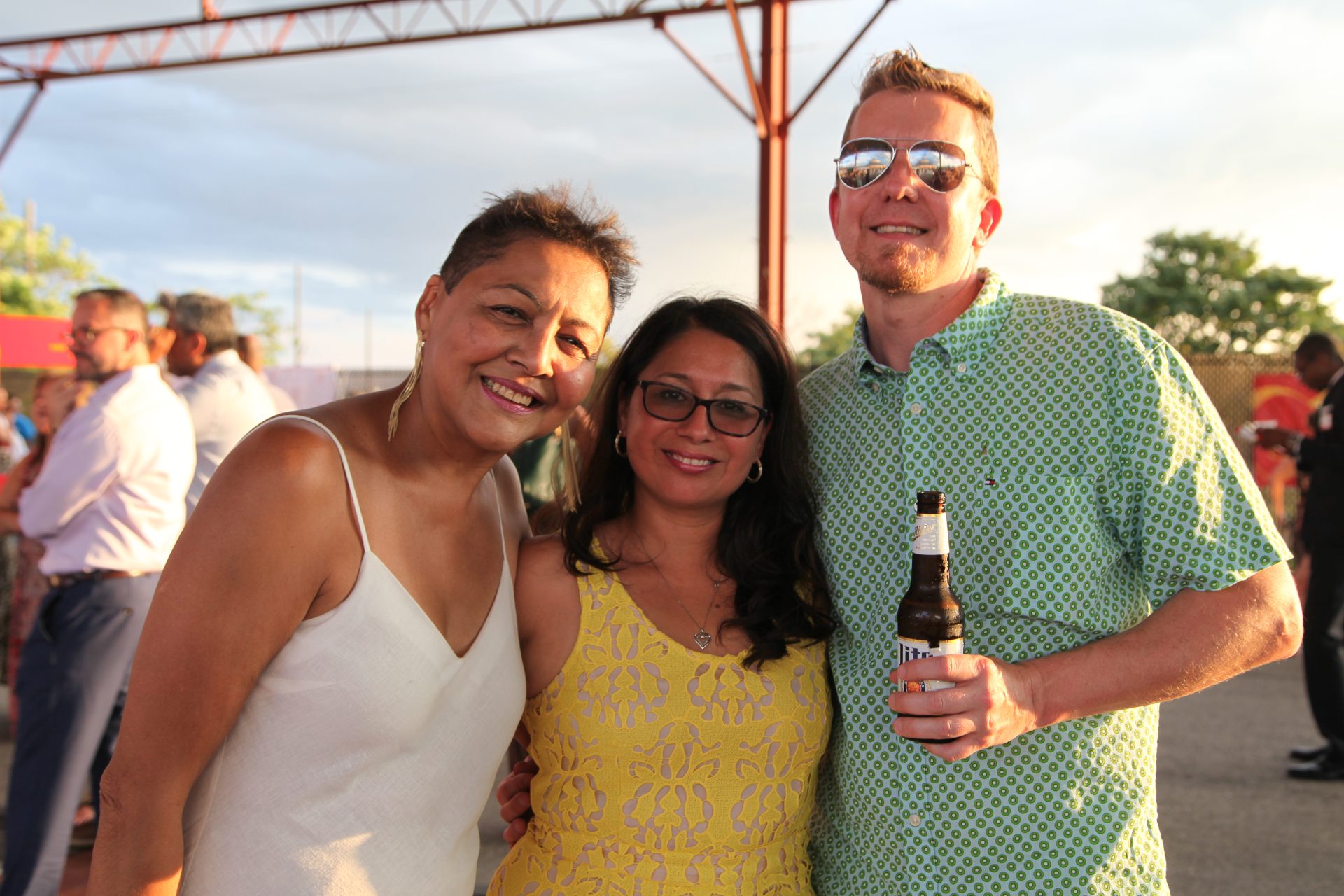 Two women pose with one man, who is holding a beer